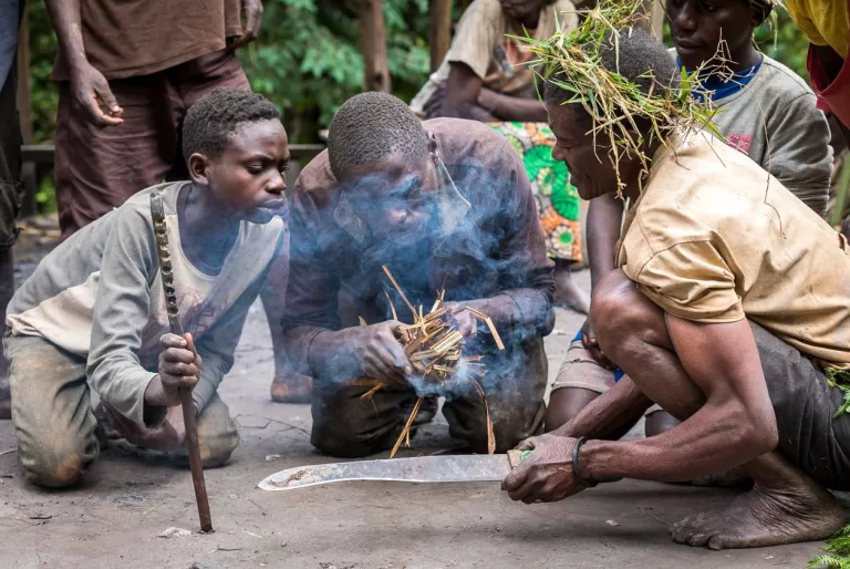 Mgahinga Gorilla National Park: Complete Guide to Gorillas, Golden Monkeys and Volcanoes Batwa guides lighting a fire with sticks on the Batwa Trail in Mgahinga Gorilla National Park
