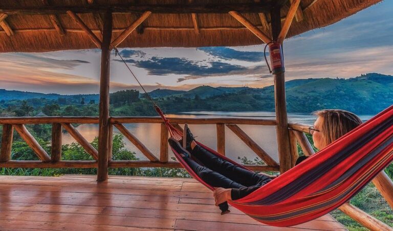Guest relaxing in a hammock above a crater lake at Crater Safari Lodge near Kibale