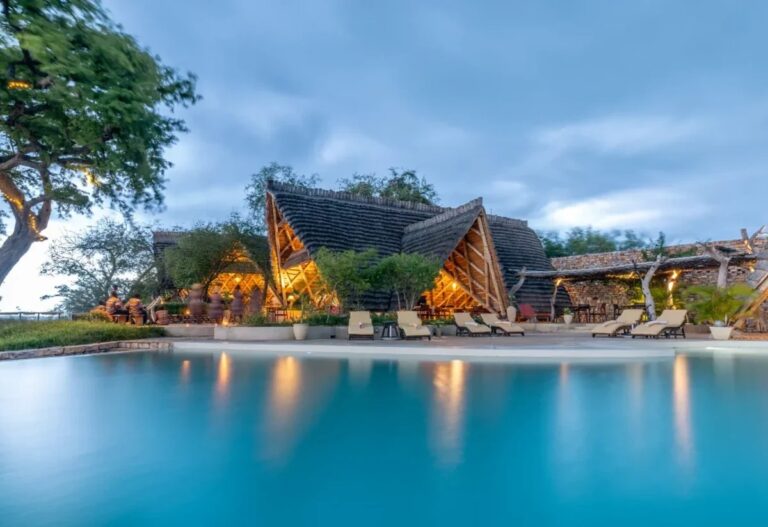 Safari lodge with a lit swimming pool at dusk in Murchison Falls National Park
