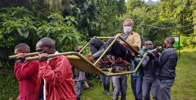 Private mountain gorilla permits trek with porters carrying a traveller in a sedan chair in Bwindi