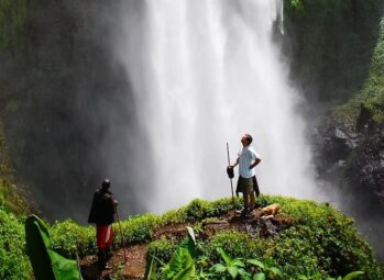 Sipi Falls Uganda: a guide and hiker at the base of the main 100-metre waterfall